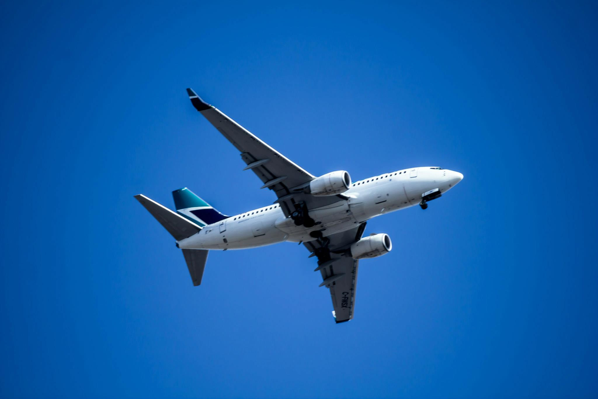 Photograph of an aircraft from below, flying high in a bright clear sky