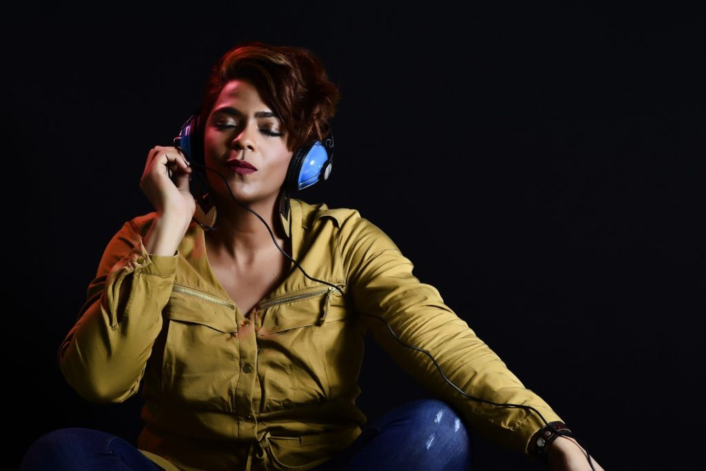 Photograph of a woman with a tranquil expression, her eyes closed, wearing blue headphones.