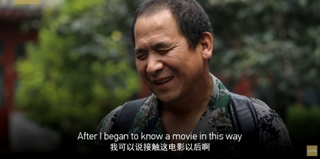 A vision-impaired Chinese man speaks to the camera. Closed Caption translation: "After I began to know a movie in this way..."